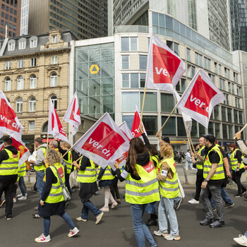 ver.di-Demonstrantenzug mit ver.di-Flaggen vor Commerzbank-Gebäude